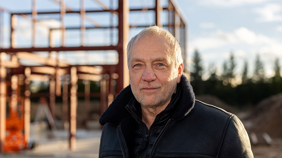 Thorsten Rebbereh, Architekt des Green Steel Home, im Porträt Porträtfoto von Thorsten Rebbereh, Architekt des Green Steel Home. Er steht vor einer Baustelle, im Hintergrund eine Stahlkonstruktion eines Gebäudes im Rohbau.