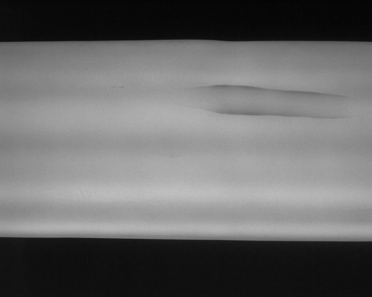 Black-and-white camera image of a bloom surface. A horizontal groove is visible at the edge of the steel roll, left as a cold cut edge defect on the bloom.