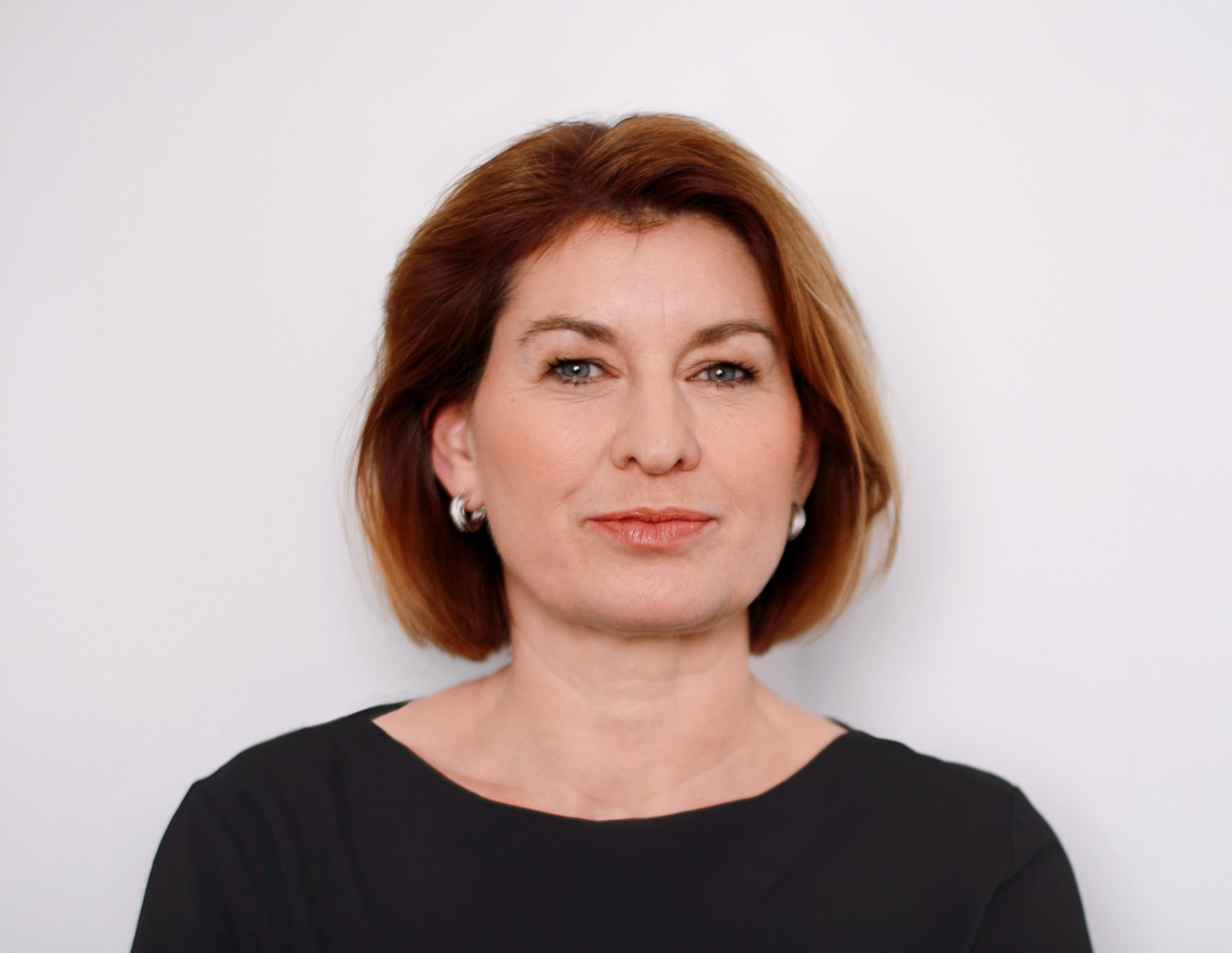 Birgit Dietze, Arbeitsdirektorin der Salzgitter AG, im Porträt Porträtfoto von Birgit Dietze, Arbeitsdirektorin der Salzgitter AG. Sie trägt ein dunkles Oberteil und eine Halskette, ihr Haar ist dunkel und kinnlang. Sie blickt selbstbewusst in die Kamera vor einem neutralen Hintergrund.