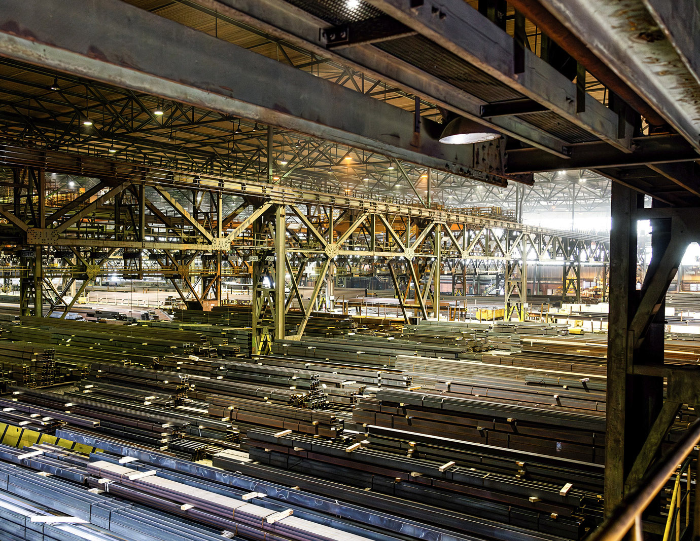 Blick in eine große, stählerne Betriebshalle mit massiven Stahlträgern und Industrieanlagen. Die dunkle, weitläufige Halle verdeutlicht die Herausforderung der Vernetzung in rauen Industrieumgebungen.