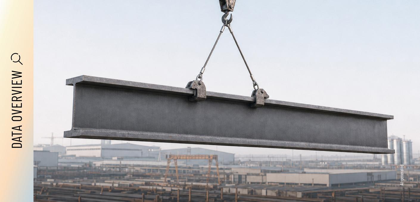 Steel beam suspended from a crane, with an industrial site in the background. A large steel beam is suspended from two lifting clamps attached to a crane, with an industrial site in the background.