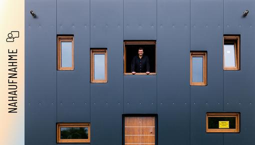 Christoph Jenner schaut aus einem Fenster der anthrazitfarbenen Stahlfassade Christoph Jenner schaut aus einem Fenster der anthrazitfarbenen Stahlfassade seines Green Steel Home .