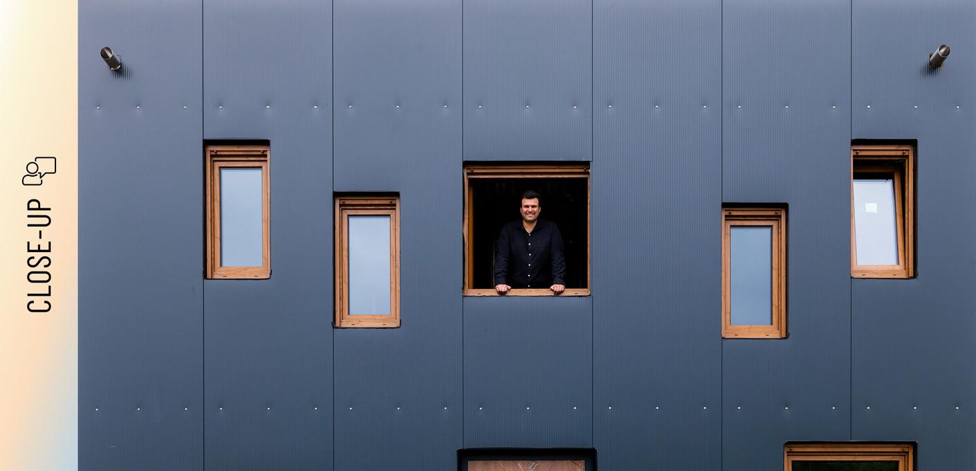 Christoph Jenner schaut aus einem Fenster der anthrazitfarbenen Stahlfassade Christoph Jenner schaut aus einem Fenster der anthrazitfarbenen Stahlfassade seines Green Steel Home .