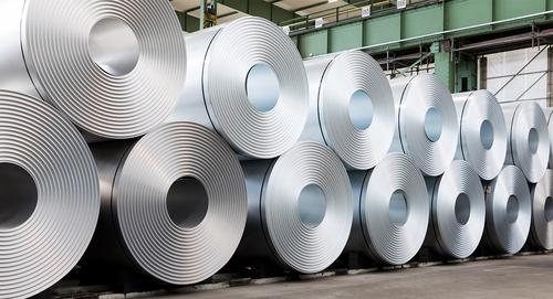 Große Stahlcoils in einer Industriehalle Mehrere große Stahlcoils lagern nebeneinander in einer Industriehalle.