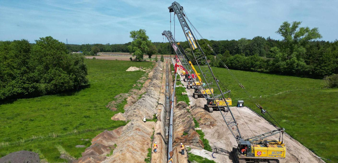 Verlegung der EWE-Zukunftsleitung. Krane halten die Pipeline, die Stück für Stück in eine Grube gelegt wird. Verlegung der EWE-Zukunftsleitung. Krane halten die Pipeline, die Stück für Stück in eine Grube gelegt wird.