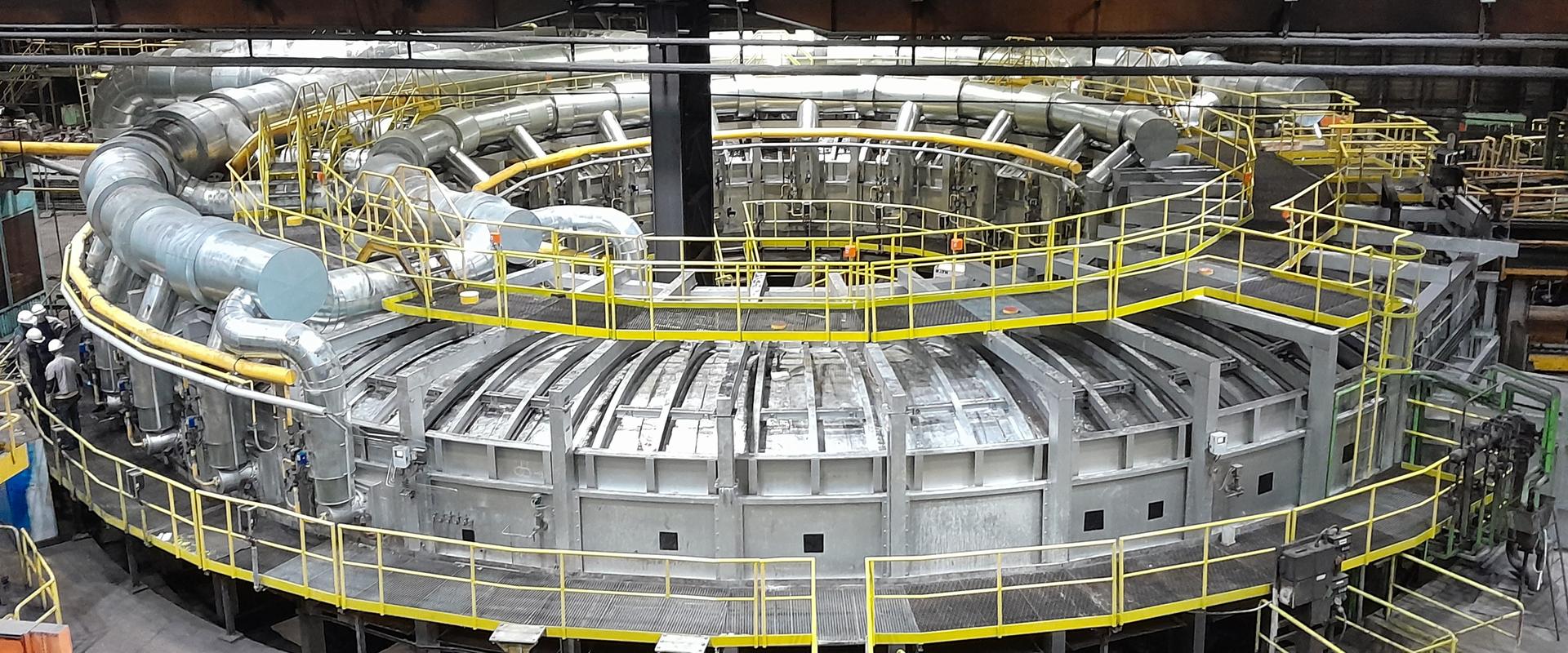 Kreisförmiger Drehherdofen in einer Werkhalle des Mannesmannröhren-Werks Zeithain, umgeben von gelben Laufstegen und Rohrleitungen.