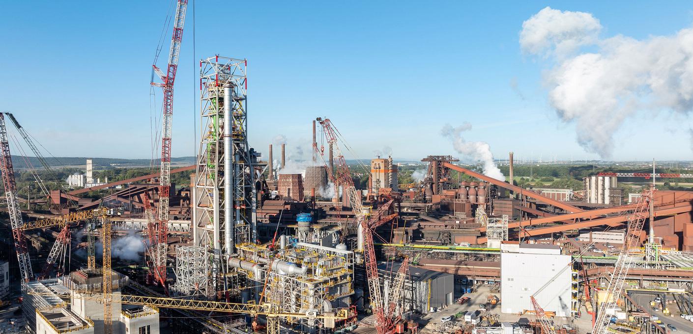 Expansive industrial site with many cranes, pipelines, and smoking chimneys on a clear day. Expansive industrial site with many cranes, pipelines, and smoking chimneys on a clear day.
