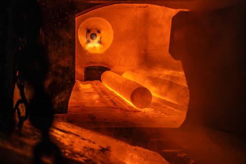 Innenansicht des Drehherdofens. Glühender, zylindrischer Stahlkörper in der orange leuchtenden Kammer eines Drehherdofens.