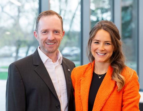 Porträt von Markus Rottwinkel und Pia Wieslinger, Verantwortliche für das Employer Branding der Sazlgitter AG Porträtfoto von Markus Rottwinkel und Pia Wieslinger, die bei der Salzgitter AG verantwortlich für das Employer Branding sind. Er trägt ein dunkles Sakko mit weißem Hemd, sie eine orangefarbene Bluse. Beide lächeln freundlich in die Kamera.