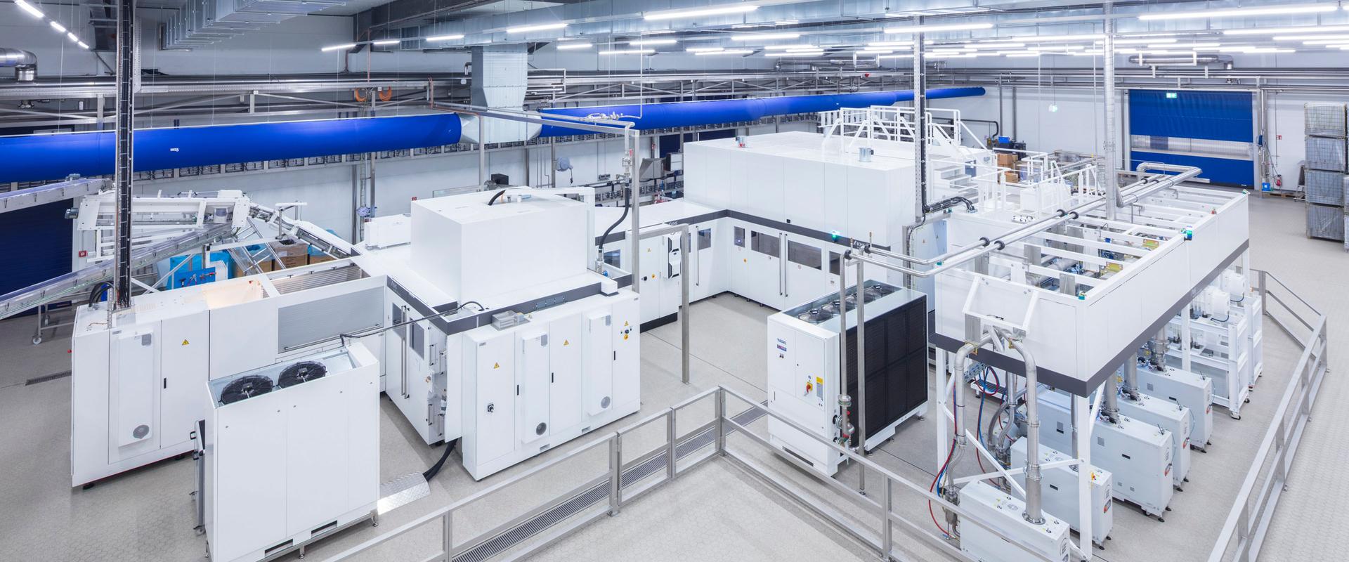 Industrielle Blockmaschine in einer hellen Produktionshalle, die Streckblasen von PET-Flaschen und deren Innenbeschichtung in einer integrierten Anlage verbindet.