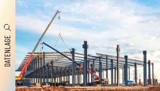 Baustelle mit Kran und Stahlkonstruktion eines Industriegebäudes.
